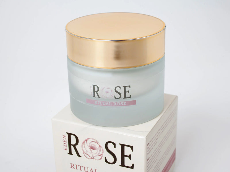 Luxury frosted glass jar of Eden Rose Ritual Rose nourishing face cream with a gold lid, sitting on top of its premium white and pink product packaging box against a clean white studio background.
